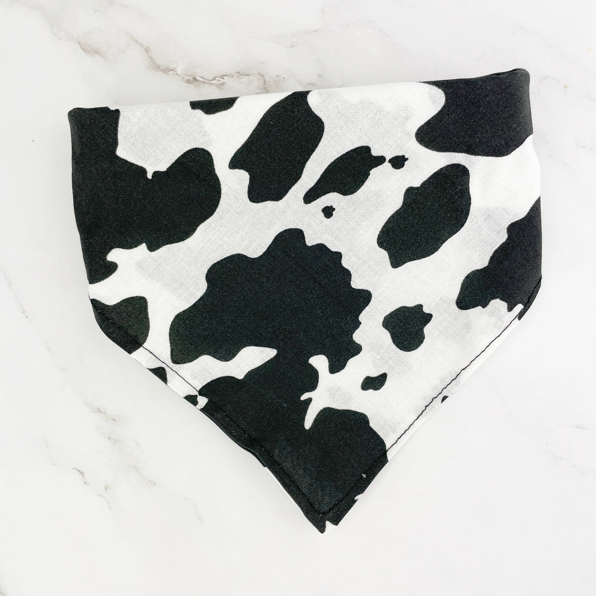 Cow print dog bandana on a marble background