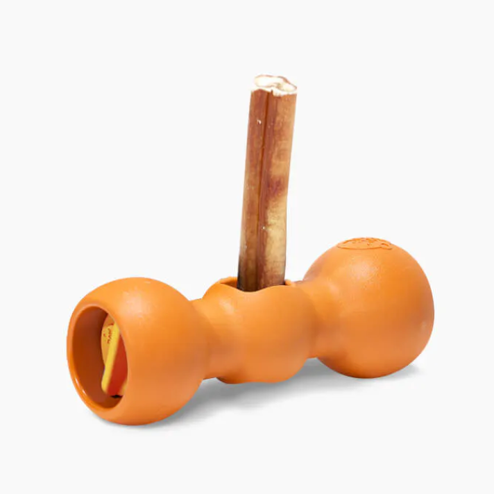 Isolated Bow Wow Buddy Bully Stick Holder Dog Toy that is a hard orange plastic and it is holding a bully stick.
