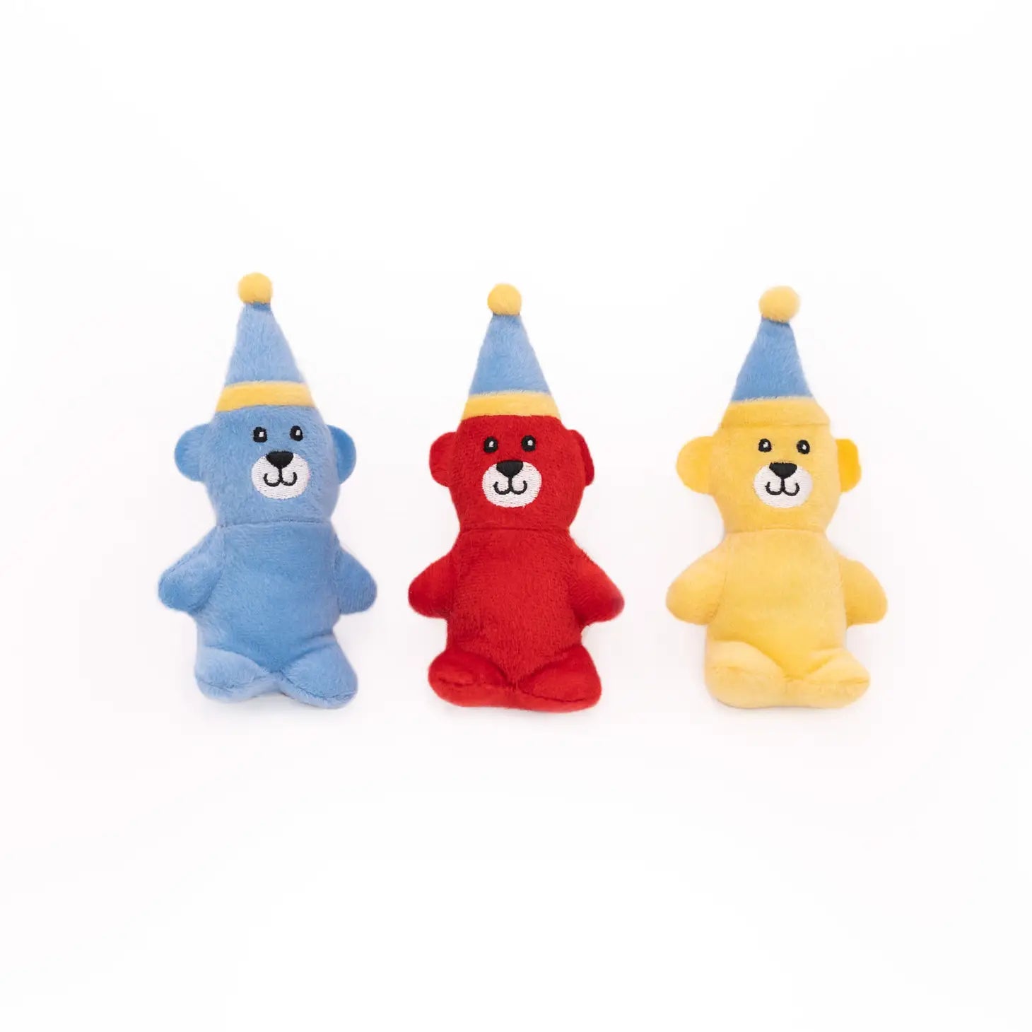 Isolated picture of three small plush bears one is blue, one is red and one is yellow. They are all wearing blue winter hats
