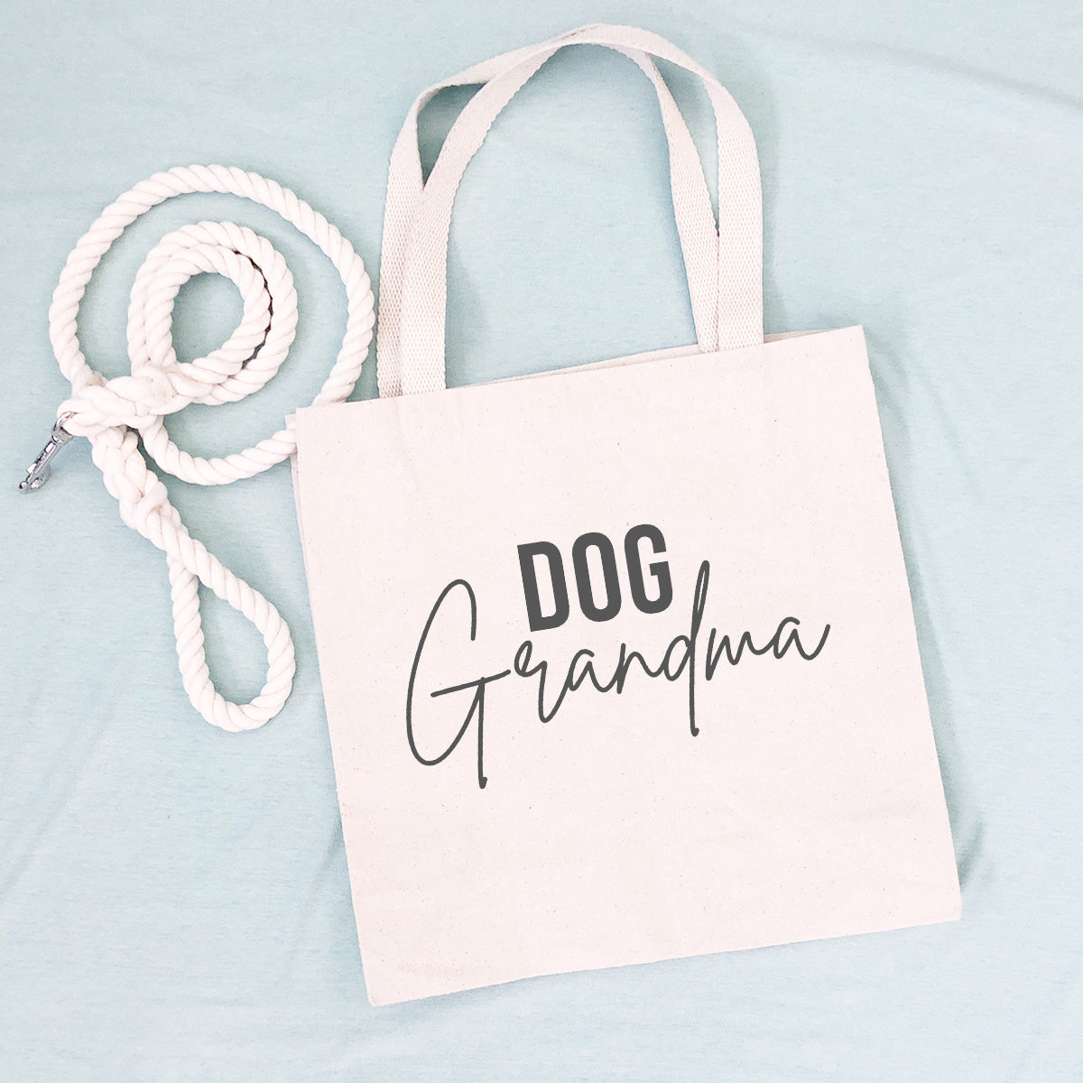 Tote bag that says "DOG Grandma" with a white leash on a blue background