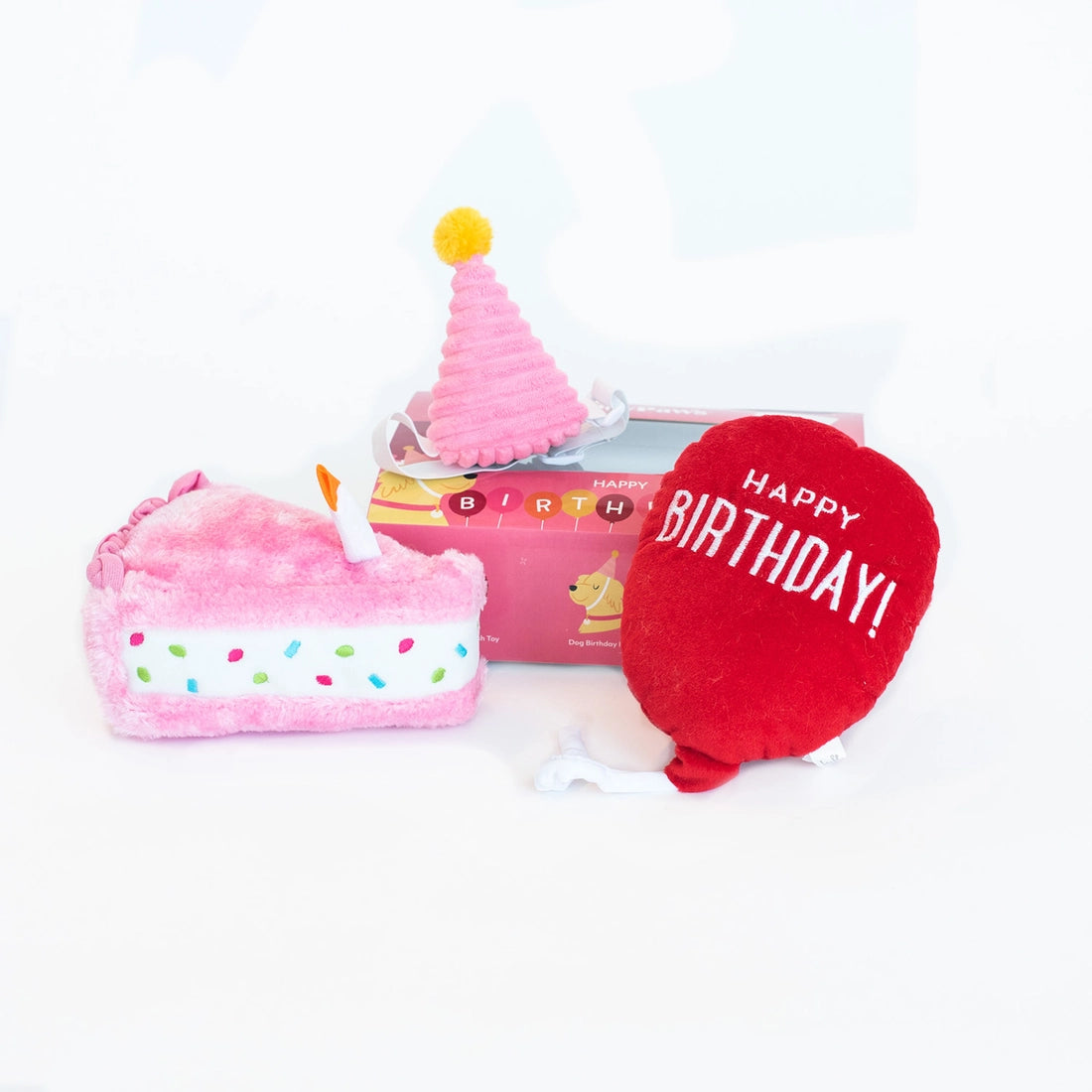 dog birthday box with a pink, plush cake slice, soft pink party hat, and a plush red happy birthday balloon toy